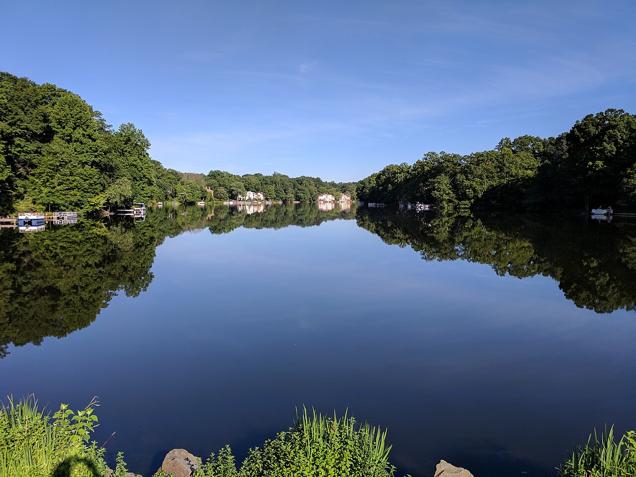 Trees and waterfront homes reflected in Lake Anne in Reston, Virginia