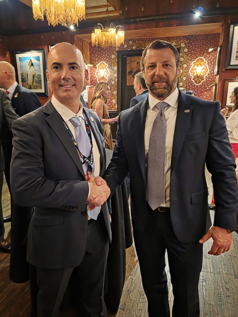 Matt Braynard and Secretary of Homeland Security Markwayne Mullin shake hands at an evening gathering in Dallas.